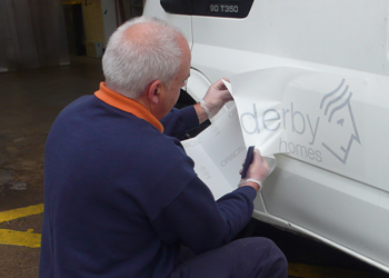 Applying vinyl lettering and logo to a Derby Homes fleet vehivle